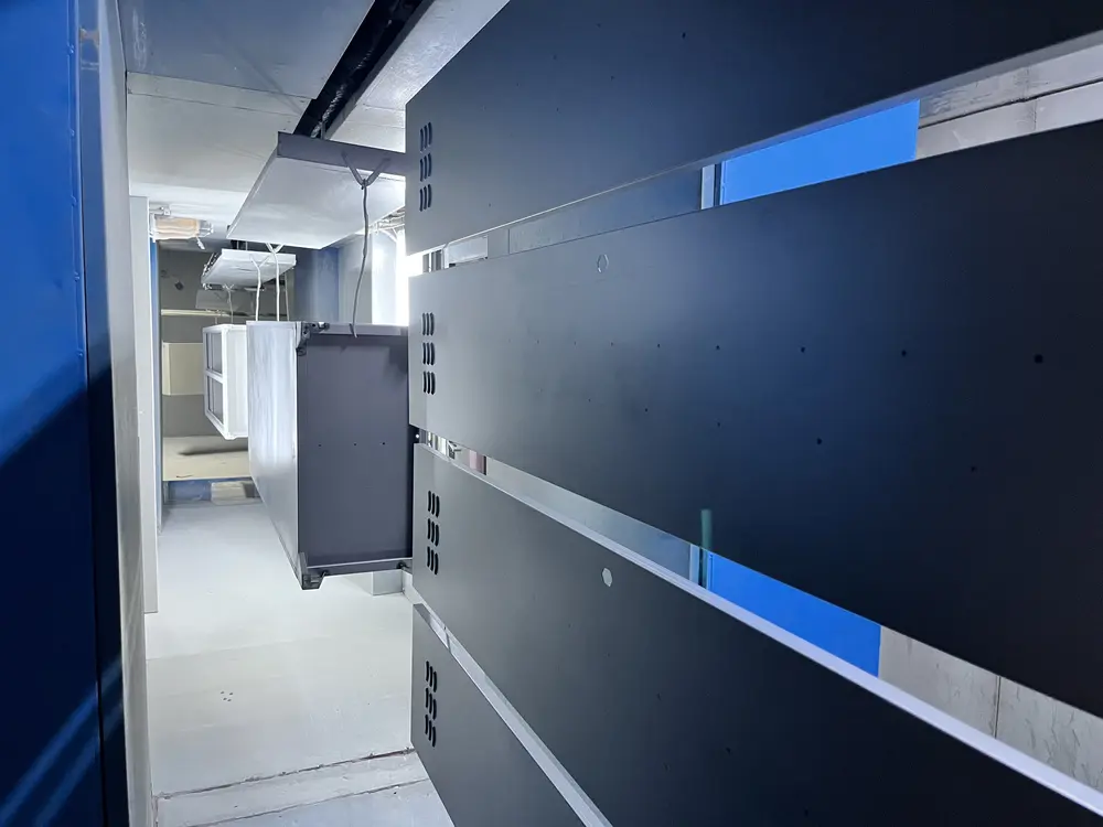 Steel locker parts on the powder-coating line, before the curing oven